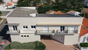 Un edificio a due piani con tetto piatto, antenna parabolica e ingresso con cancello.