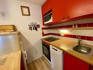 A compact kitchen with red cabinets, a microwave, a sink, and a dishwasher.
