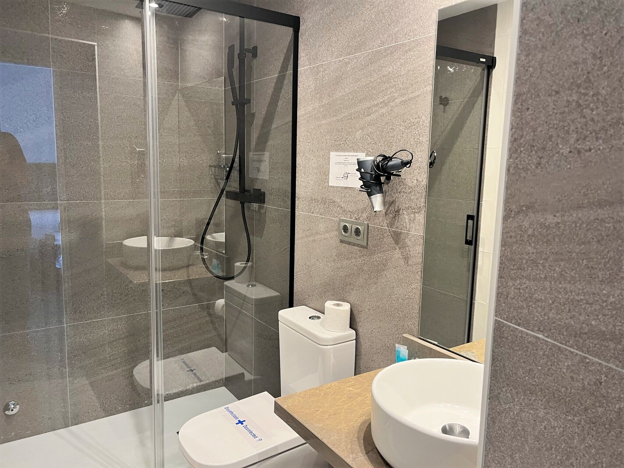 A modern bathroom with a glass-enclosed shower, a white toilet, and a large sink.