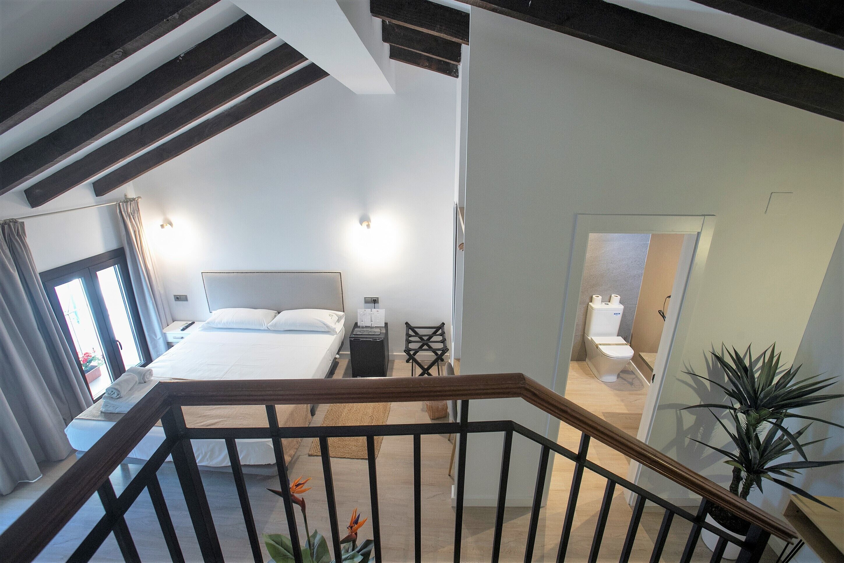 A modern bedroom with a large bed, bedside tables, a mirror, and a view of the bathroom.