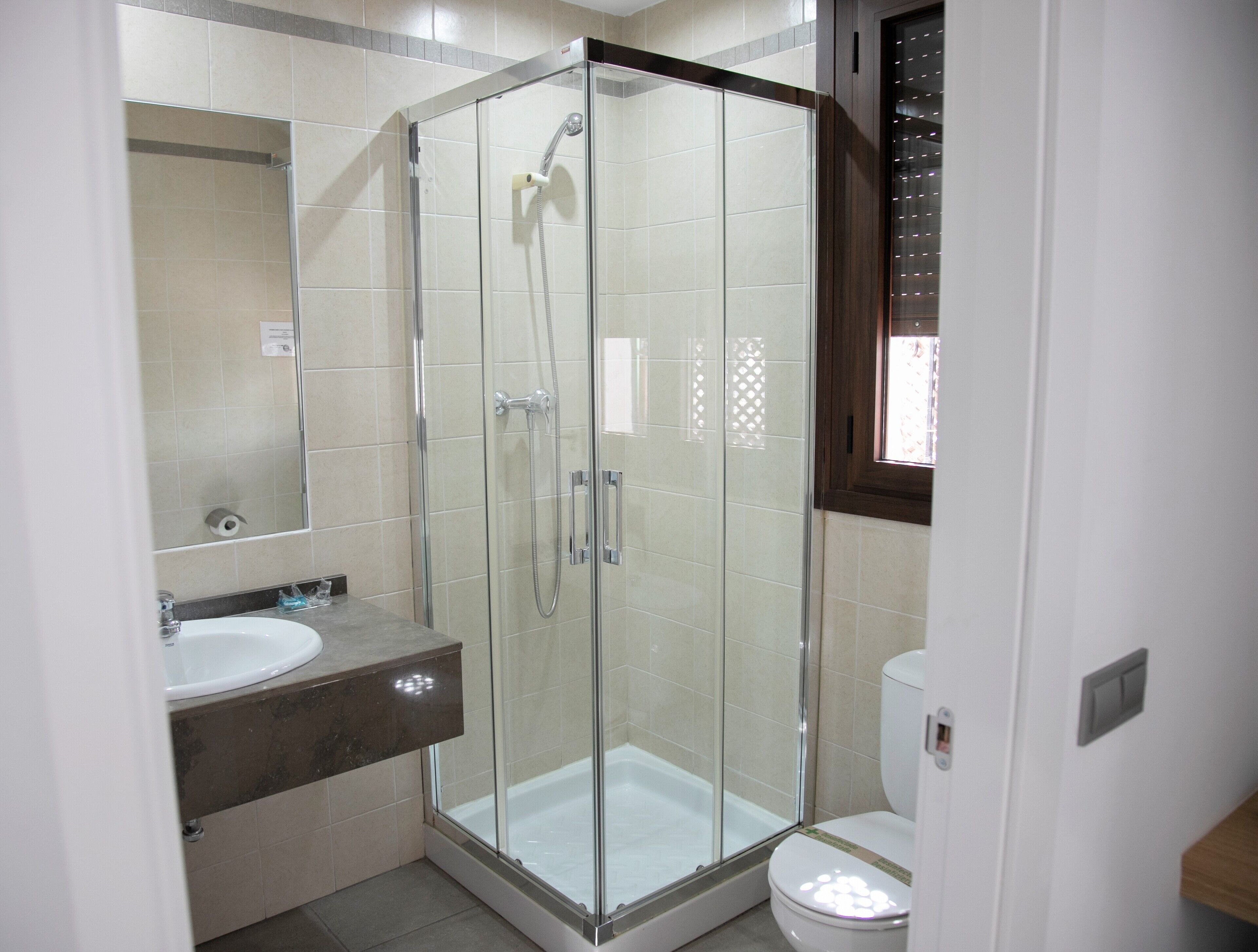 A modern bathroom with a glass-enclosed shower, a sink, and a toilet.