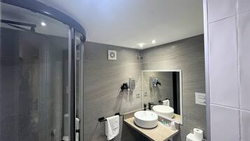 A modern bathroom with a glass shower enclosure, a double sink vanity, and a toilet.