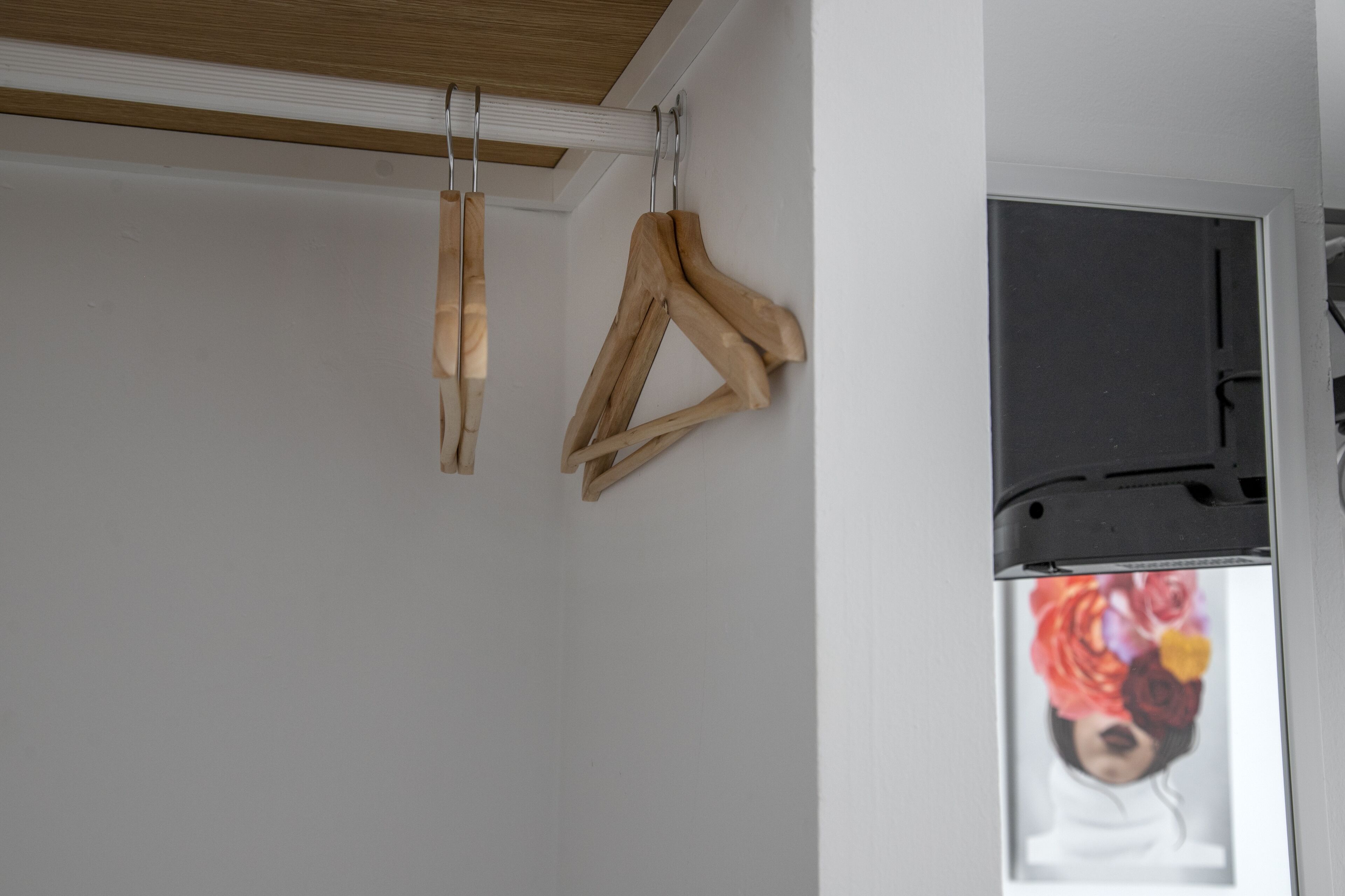 A room with a white wall, a wooden ceiling, and a door with a black frame.