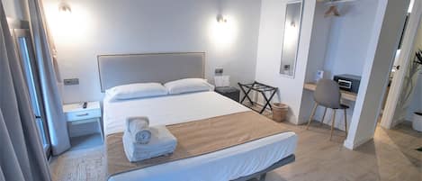 Una habitación de hotel moderna con una cama grande, mesitas de noche, un escritorio y una silla.