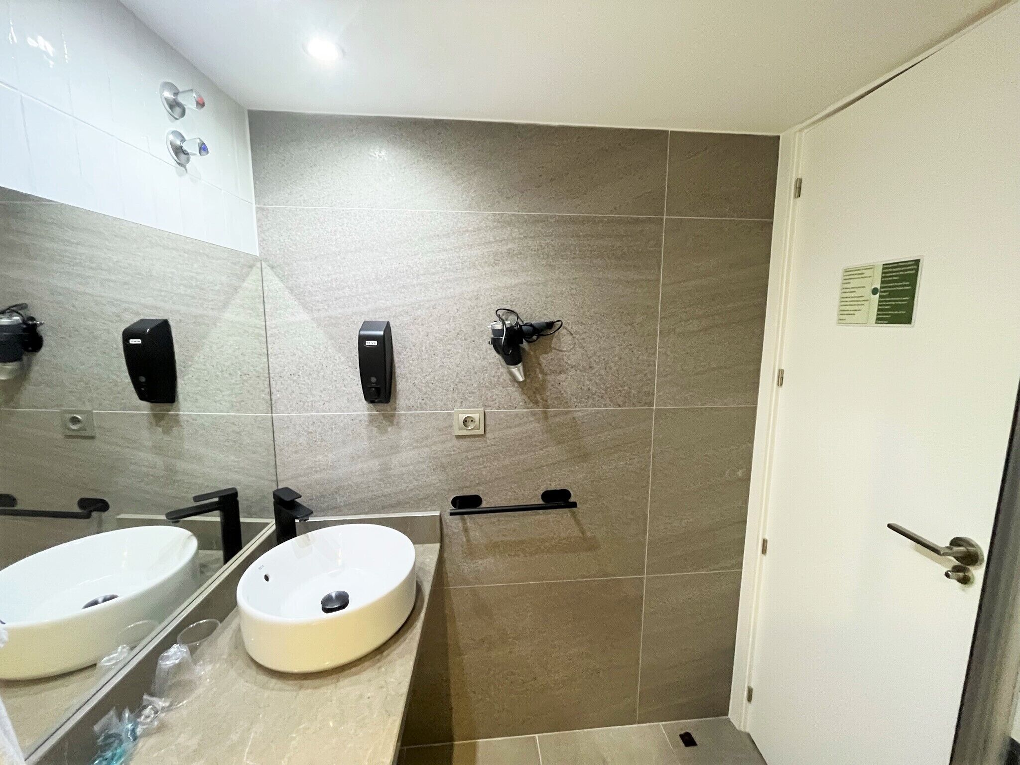 A modern bathroom with two sinks, a mirror, a towel rack, and a toilet.