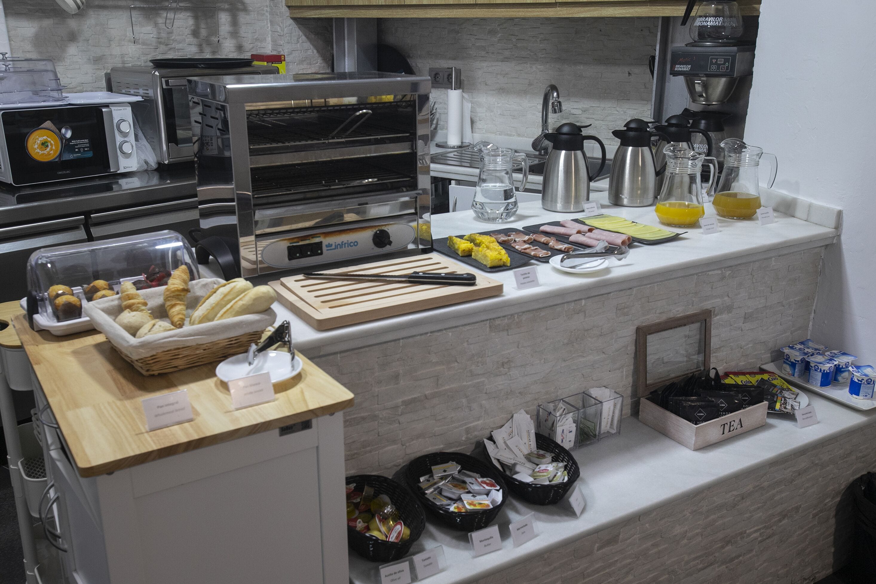 Un bufé de desayuno con diversas opciones de alimentos, una cafetera y una estación de té.