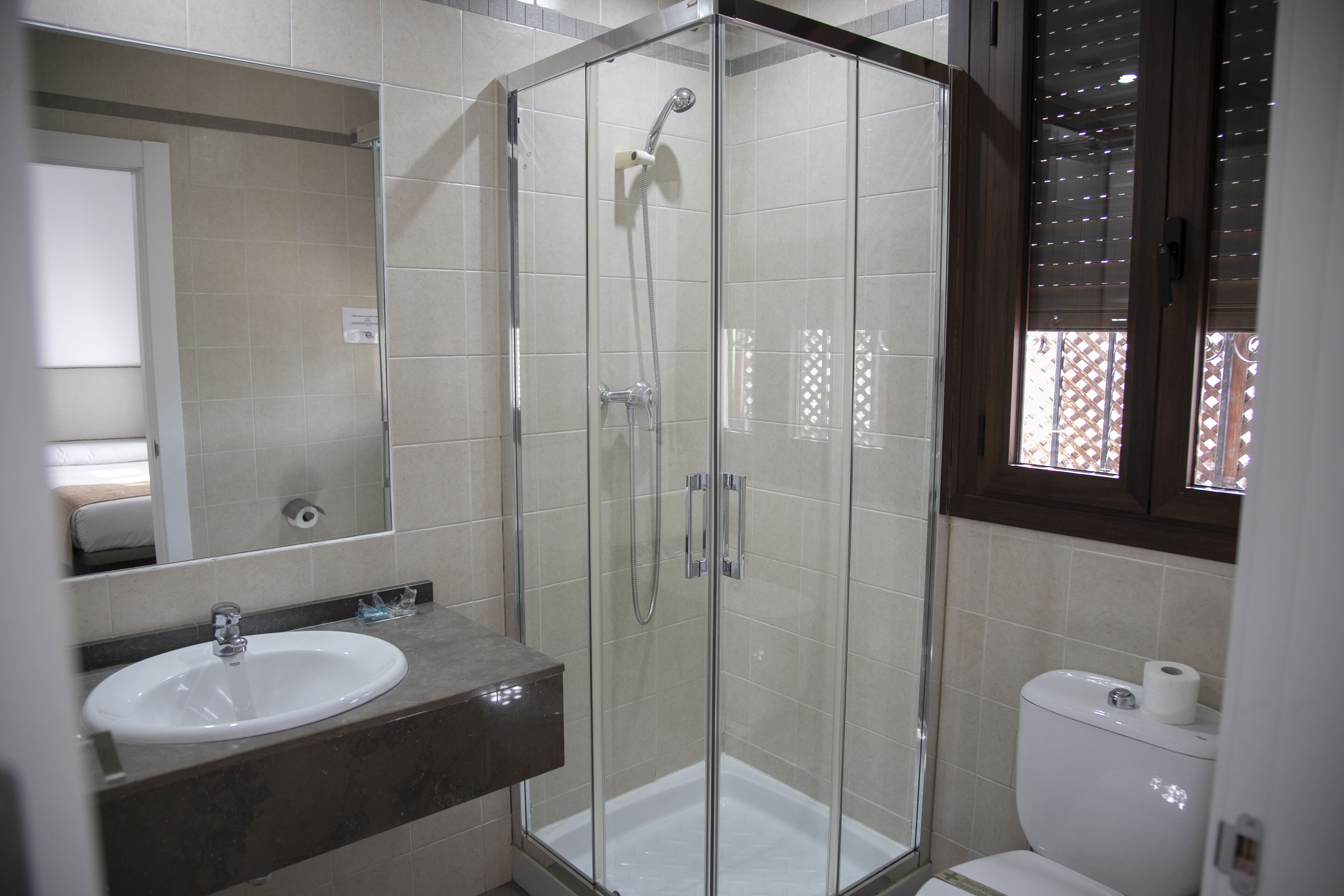 Een badkamer met een glazen douchecabine, een wastafel en een toilet.