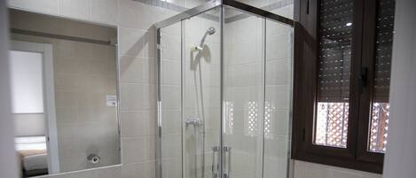 Een badkamer met een glazen douchecabine, een wastafel en een toilet.