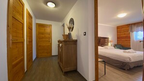 Ein Schlafzimmer mit hölzernem Kopfteil, einem Bett mit weißen Leinentüchern, einem Nachttisch und einem Spiegel an der Wand.