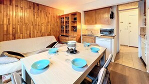 Un comedor con una mesa de madera para cuatro personas, un sofá y una cocina al fondo.