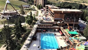 Un resort con una amplia piscina, zona de juegos para niños y restaurante.