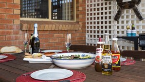 Een eettafel gedekt met borden, bestek, een saladeschaal en flessen drank.