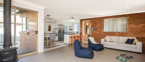 A living room with a sofa, blue bean bag chairs, a fireplace, and a kitchen in the background.