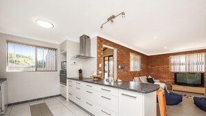 Een moderne keuken met witte kastjes, een centraal eiland en een accentmuur van baksteen.