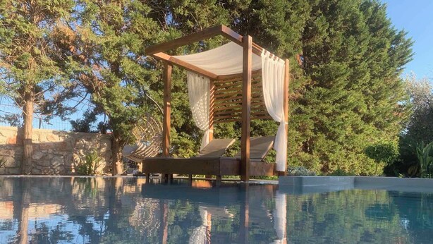 A pool with a wooden pergola and two lounge chairs. - 3 Roses Residence in Afandou (Αφάντου)