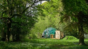 A dome-shaped structure surrounded by lush greenery, likely a yurt or similar accommodation, with a wooden fence and a small shed nearby. - Hever Luxury Dome (Hoath)