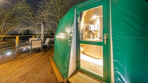 A green tent with a kitchen area visible through the door, a wooden deck with chairs, and a railing. - Hever Luxury Dome (Hoath)