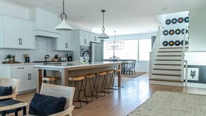 Una cocina moderna con armarios blancos, una isla central con taburetes y una zona de comedor con mesa y sillas.