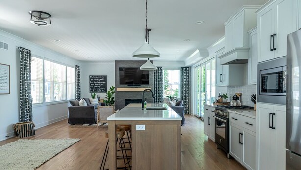 Una cocina moderna con armarios blancos, una isla central y electrodomésticos de acero inoxidable.