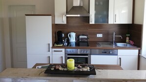 Una cocina moderna con armarios blancos, una estufa de acero inoxidable y un horno empotrado.