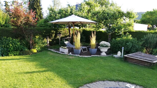 Un jardín bien cuidado con un patio empedrado, mobiliario exterior y un elemento decorativo de piedra.