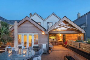 Una casa moderna con un patio, un comedor y una cocina visibles a través de las puertas de vidrio.