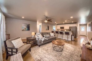 A modern living room with a sofa, coffee table, and a kitchen in the background.