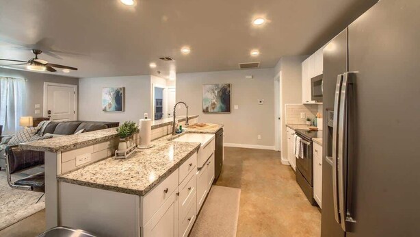 A modern kitchen with granite countertops, stainless steel appliances, and recessed ceiling lighting. - RR 464 Sattler Haus (New Braunfels)