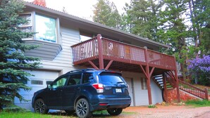 A blue SUV parked in front of a house with a wooden deck and a garage. - CASCADE RETREAT IN MOUNTAIN SETTING, NEAR PIKES PEAK, MINUTES TO MANITOU SPRINGS (Manitou Springs)