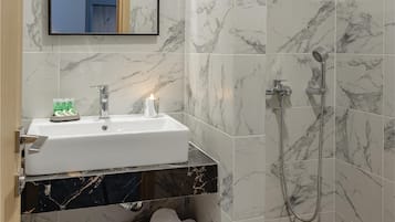 A bathroom with a marble sink, a mirror, a shower, and a towel rack.