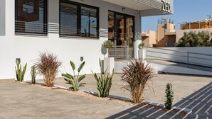 A modern building with a clean facade, a gated entrance, and a small garden with various plants. - Zed Smart Property by Airstay (Spata-Artemida)