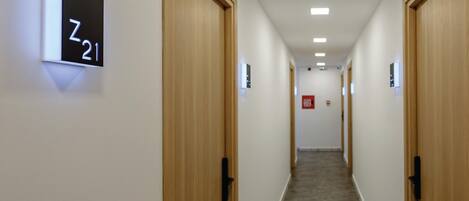 Un couloir avec des portes en bois, un sol recouvert de moquette et une pancarte indiquant le numéro de la pièce : Z21.