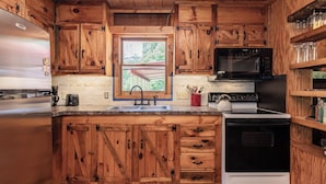 A kitchen with wooden cabinets, a stainless steel refrigerator, a microwave, a stove, and a sink. - Twin Creeks Cabin - RIVER FRONT! *Hot tub* 4 acres! Pets OK (Deep Gap)