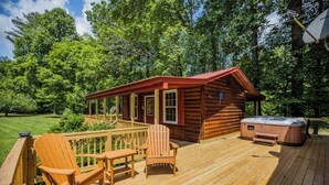 A wooden cabin with a deck, a hot tub, and outdoor seating. - Twin Creeks Cabin - RIVER FRONT! *Hot tub* 4 acres! Pets OK (Deep Gap)