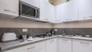 Una cocina moderna con armarios blancos, un microondas integrado, una estufa a gas y un lavabo.