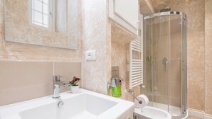 Un baño con una bañera blanca grande, un inodoro blanco independiente y una cabina de ducha con paredes de vidrio.