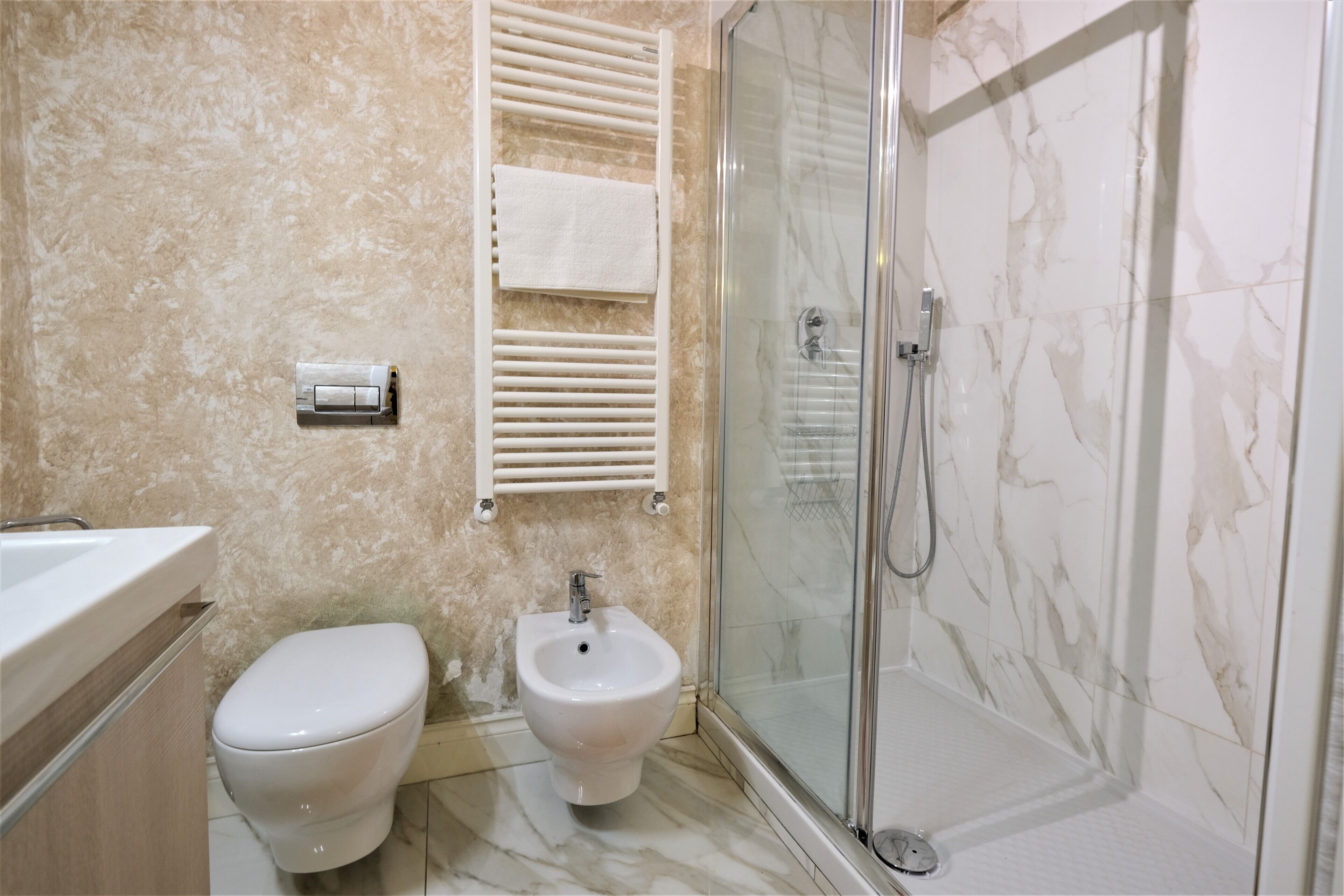 A bathroom with a toilet, bidet, and a glass-enclosed shower area.