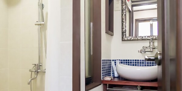 Un baño con ducha, lavamanos y espejo.