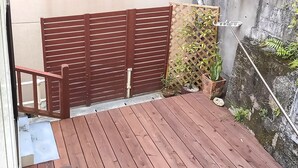 A wooden deck with a sliding door, a potted plant, and a stone wall.