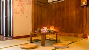 A traditional Japanese room with tatami flooring, a low table with cushions, and a wooden door.