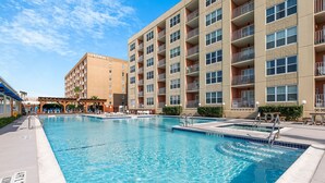 A hotel with a swimming pool, a covered area, and a building with multiple balconies.
