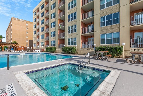 A hotel with a pool area, including a smaller pool and lounge chairs.