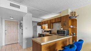 A modern kitchen with wooden cabinets, a central island, and blue chairs.