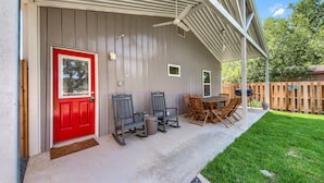 Un patio cubierto con una puerta roja, asientos exteriores y un ventilador de techo.