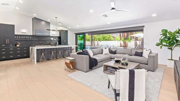 A modern living room with a grey sectional sofa, a coffee table, and a bar area with stools. - Designer Retreat | Heated Pool & Chefs Kitchen (Scottsdale)