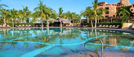 Piscina com cadeiras de descanso e palmeiras, cercada por edifícios.