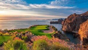 Un campo da golf con una distesa d'acqua e scogliere rocciose.