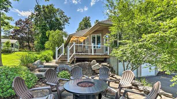 A patio with Adirondack chairs and a fire pit, surrounded by a stone deck and greenery. - Walk to Lake: Middlefield Home w/ Fire Pit (Middlefield)