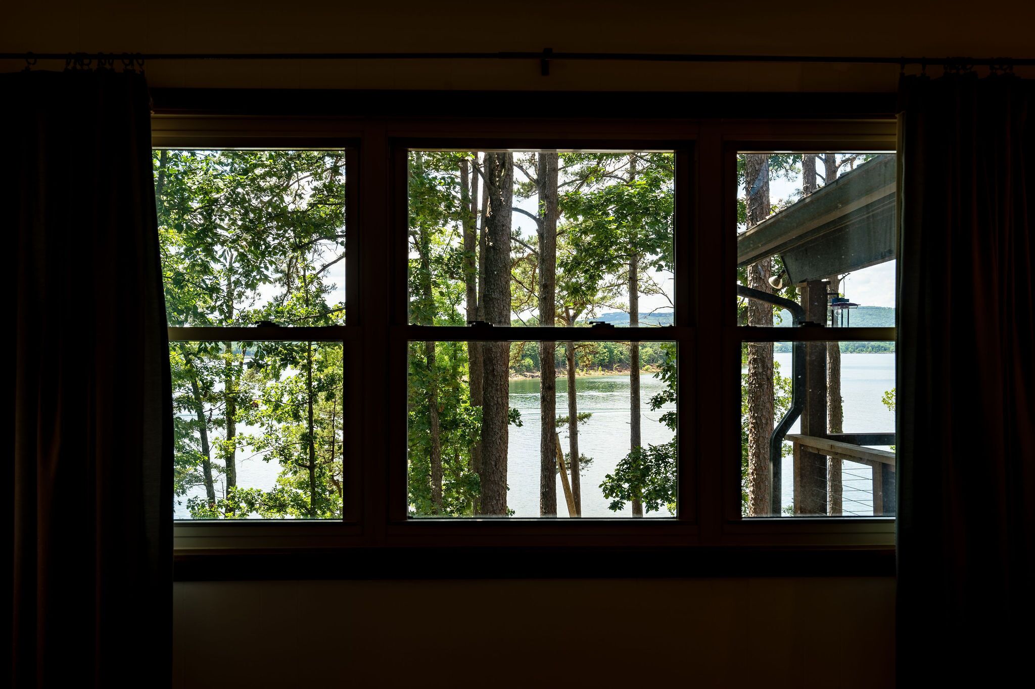 A window with a view of trees and a body of water.