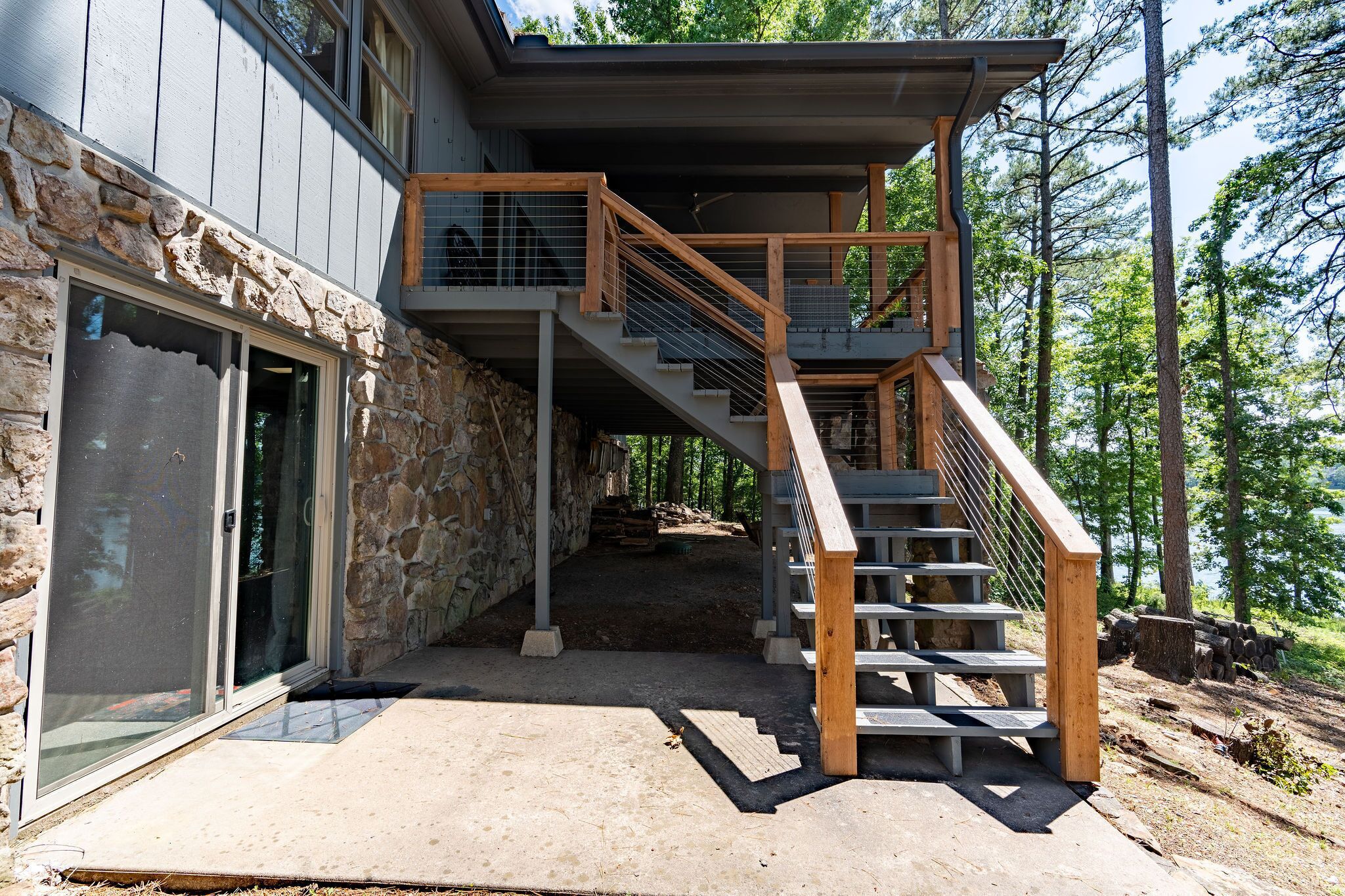 Ein modernes Haus mit Natursteinfassade, einer Holztreppe und einer Glastür.